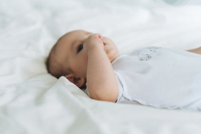 Cute baby girl 2-4 month on bed with white linen, natural tones, selective focus