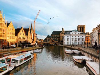 Boats moored in river against buildings in city
