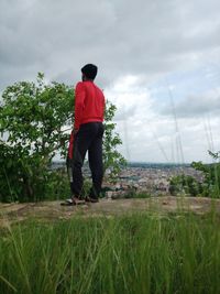 Rear view of man standing on field against sky