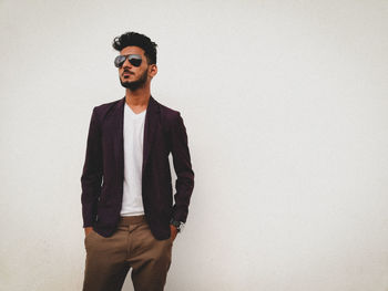 Portrait of young man standing against wall