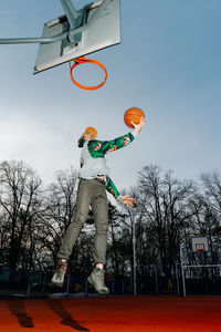 Low angle view of man playing basketball against sky