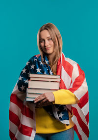 Portrait of woman holding american flag against clear blue background