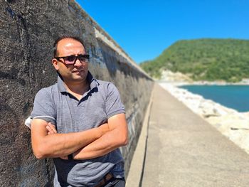 Portrait of young man wearing sunglasses standing against sky