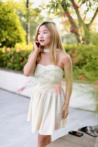 Portrait of young woman standing against trees