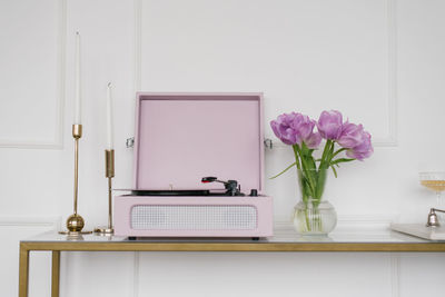 Beautiful lilac tulips in a glass vase, retro record player and candles in the living room