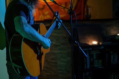 Midsection of man playing guitar