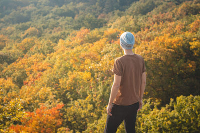 Man looks at the leafy trees playing with all the colors of autumn. wild sarka, prague, czechia