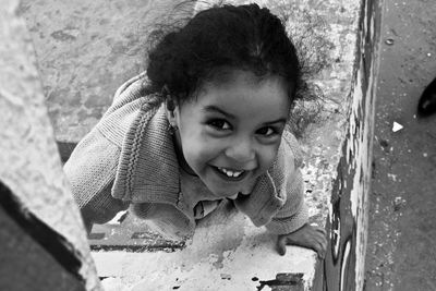 Portrait of smiling girl playing on retaining wall