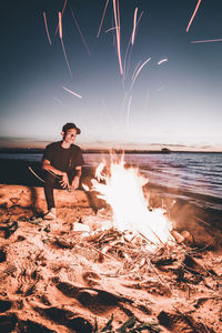 Man standing at beach against sky at night