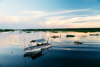 Boats moored in calm lake at sunrise