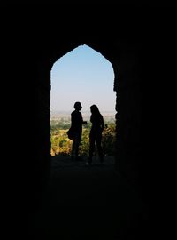 Silhouette of people at archway against clear sky