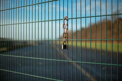 Close-up of closed chain on metal fence against blurred background