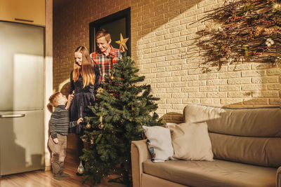 Family standing by christmas tree at home