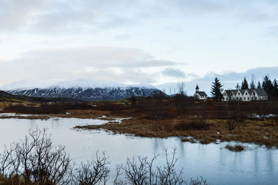 Scenic view of lake by snowcapped mountains against sky