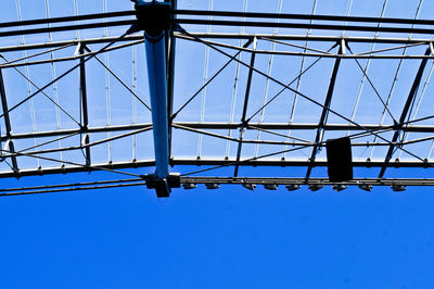 Low angle view of electricity pylon against clear blue sky