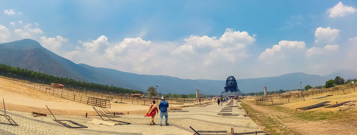 Rear view of people walking on land against sky