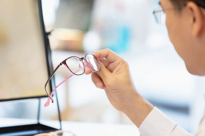 Close up eyeglasses in hands, man professional optician selling holding spectacles in clinic.