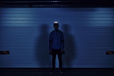 Rear view of man standing against illuminated wall