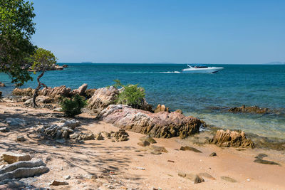 Speed boat on turquoise sea by ko man klang with mangrove forest against blue sky, rayong, thailand.