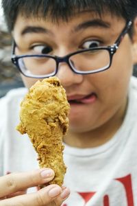 Close-up of teenage boy licking lips while holding fried chicken