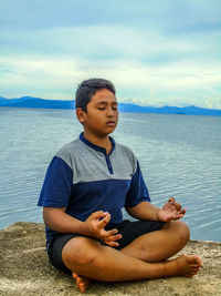 Man sitting in sea against sky
