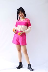 Full length portrait of a smiling young woman over white background