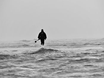 Man surfing on sea against clear sky