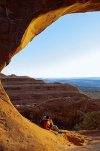 Hiker looking out of an arch at arches national park