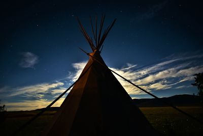 Low angle view of silhouette tent on field against sky at night