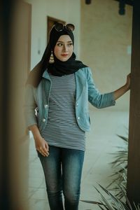 Portrait of young woman standing against wall