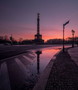 Reflection of building in puddle at sunset