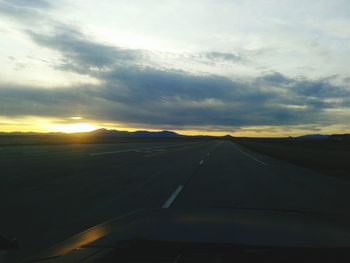 Scenic view of landscape against cloudy sky at sunset