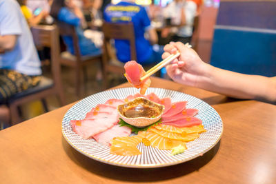 Close-up of hand holding ice cream on table