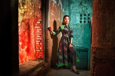 Portrait of young woman standing by wall