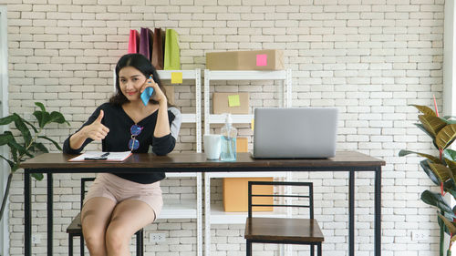 Young woman using phone while sitting on table