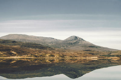 Scenic view of lake by mountains against sky