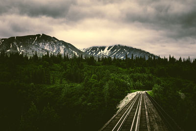 Railroad tracks by mountain against sky