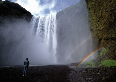 Man standing in front of skogarfoss waterfall in iceland