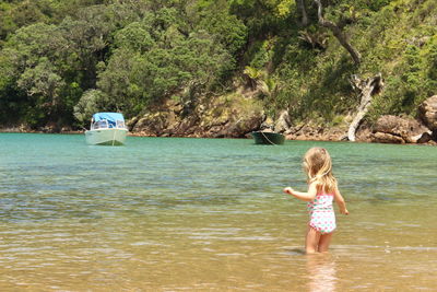 Girl standing in river against mountain on sunny day