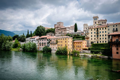 Buildings by lake against sky