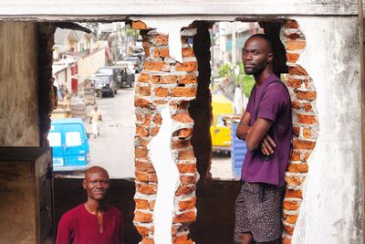 Portrait of men standing by old brick walls