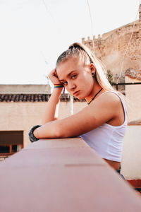 Portrait of beautiful young woman sitting against wall