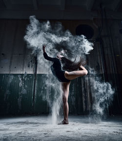 Full length of woman powder dancing in abandoned house