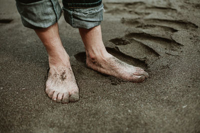 Low section of man standing on sand