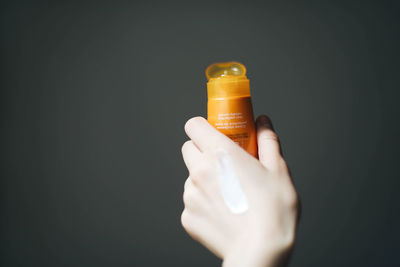 Close-up of hand holding bottle against black background