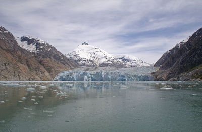 Scenic view of lake by snowcapped mountains against sky