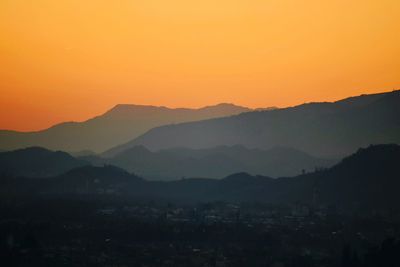 Scenic view of silhouette mountains against orange sky