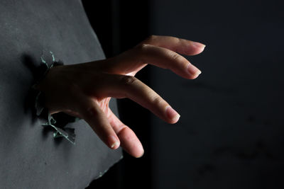 Cropped hand of person gesturing against black background