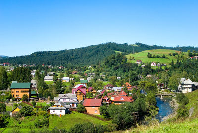 Scenic view of houses and trees against clear blue sky