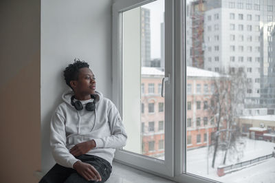 Young man looking through window